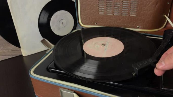 一名男子将黑胶唱片放在电唱机的光盘上。将拾取针设置到光盘轨道并开始播放。