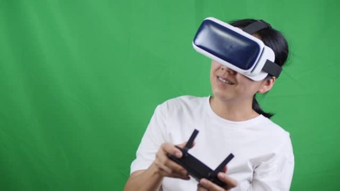 亚洲女性在绿屏上使用VR眼镜和控制无人机