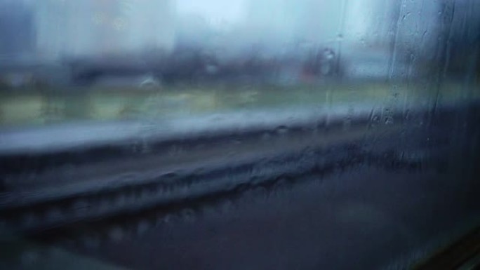 窗户上的雨滴。铁路。模糊的城市交通。路灯。