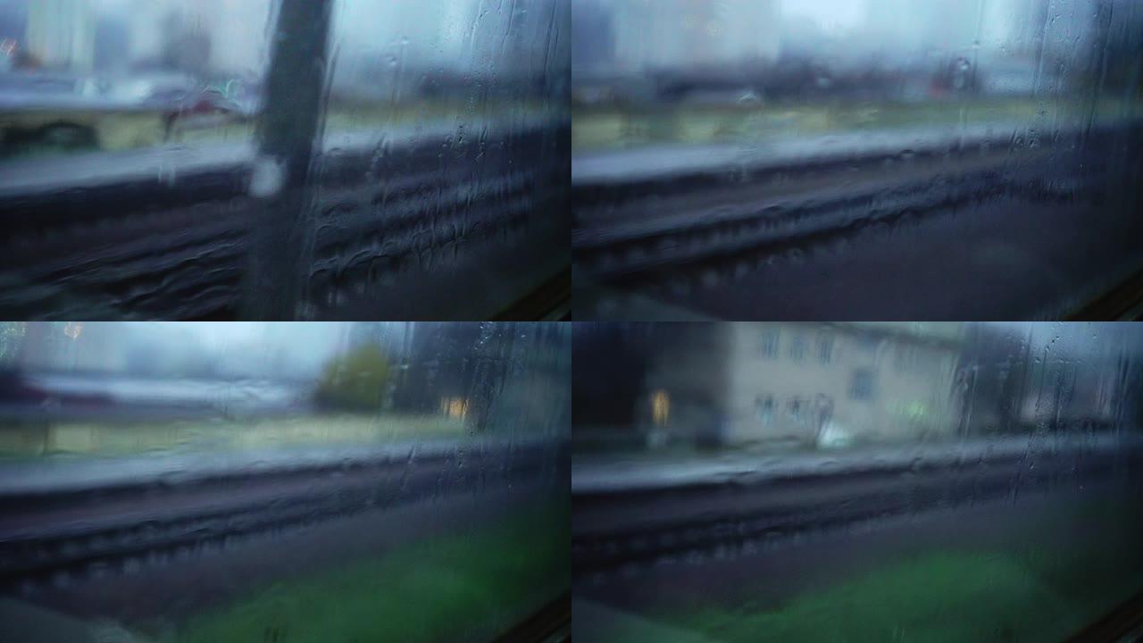 窗户上的雨滴。铁路。模糊的城市交通。路灯。