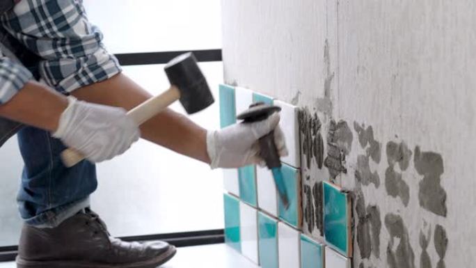 4k亚洲高级杂工使用凿子和锤子剥离陶瓷墙砖。高级技术员修理建筑工程或家庭装修。资深老人DIY工作理念