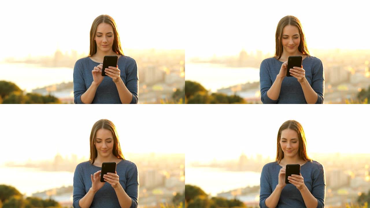 日落时使用智能手机的女人的前视图