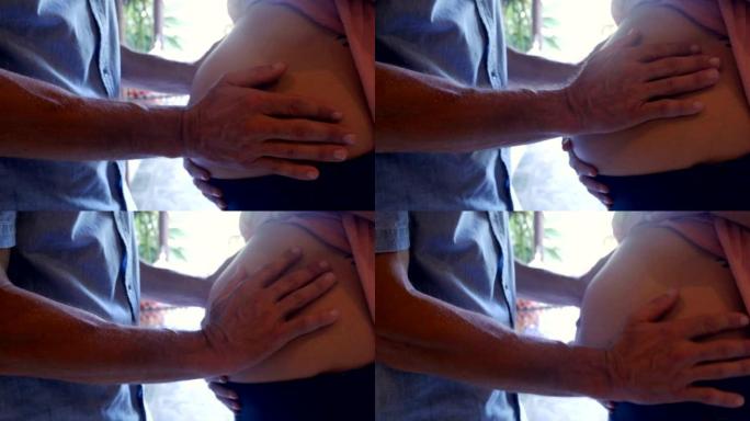 一个男人用双手抚摸女人怀孕的肚子的特写