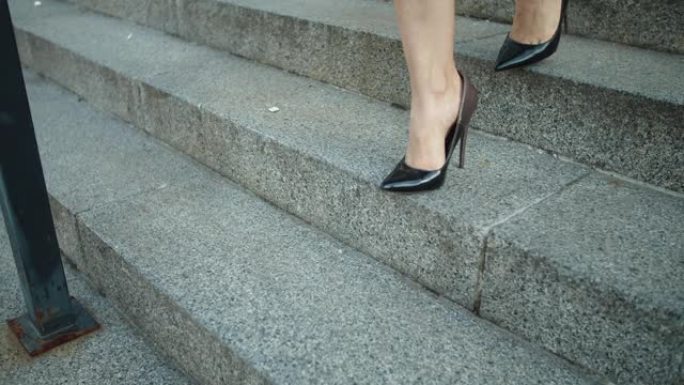 特写女性的脚在鞋子下楼梯。穿高跟鞋走路的女人