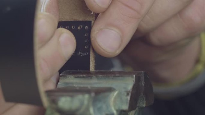 男用手缝制黑色皮革手工表带的特写针，制造过程中的优质商品。电影院4k视频。C4K