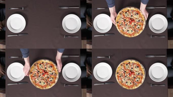 男性手的俯视图将一个装有美味披萨的盘子放在比萨店的桌子上。意大利传统饮食概念