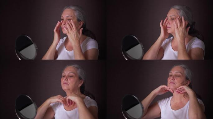 年长的女人在镜子里看到并在脸上涂上奶油