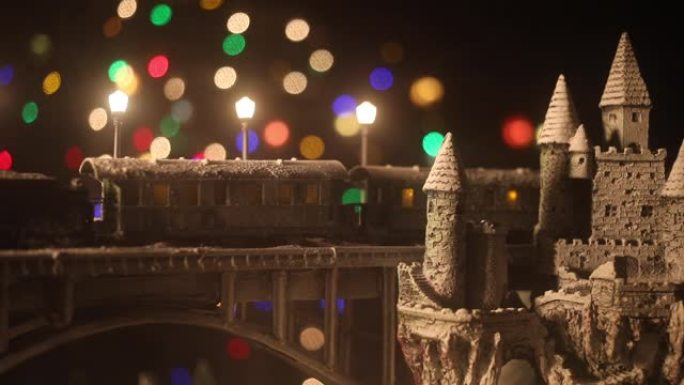 冬季雪景的缩影，火车在桥上，中世纪城堡和小城市。假日属性。夜景。新年和圣诞节的概念。创意艺术品迷你桌