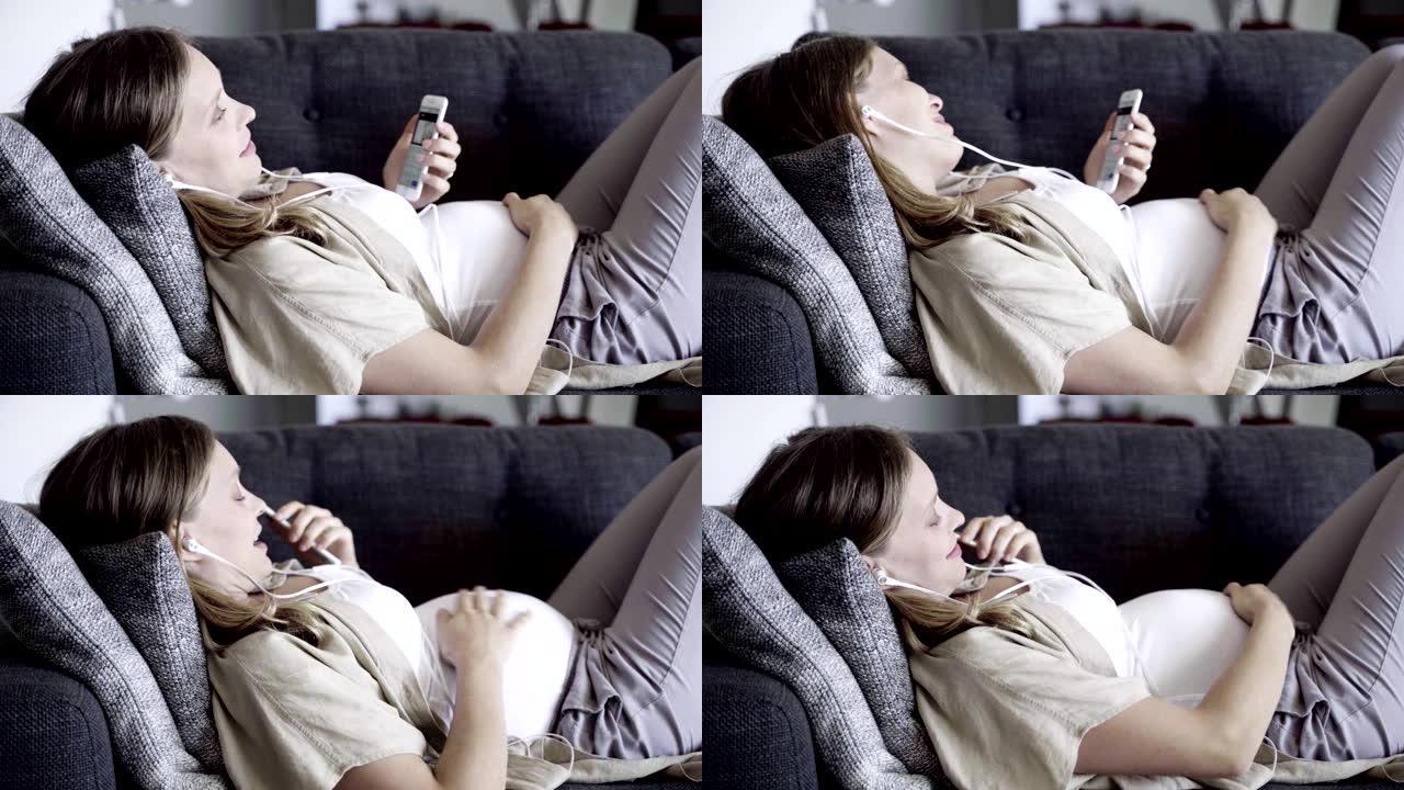 微笑的孕妇躺在沙发上有视频通话