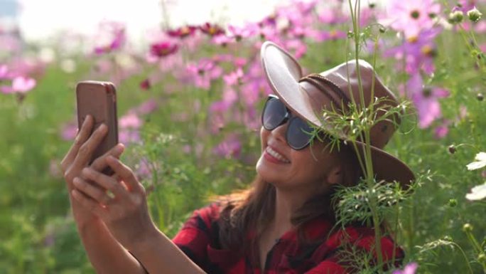 宇宙草地上亚洲成熟女性的面部表情，另类生活方式放松，退休，使用智能手机拍照带花