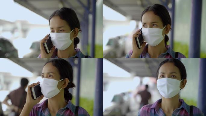 年轻的亚洲女人玩智能手机与面罩保护免受不良污染和病毒。