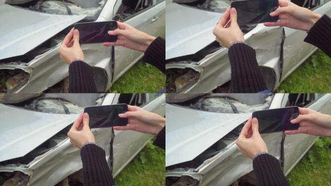 一辆破车撞车后，女人在智能手机上拍照