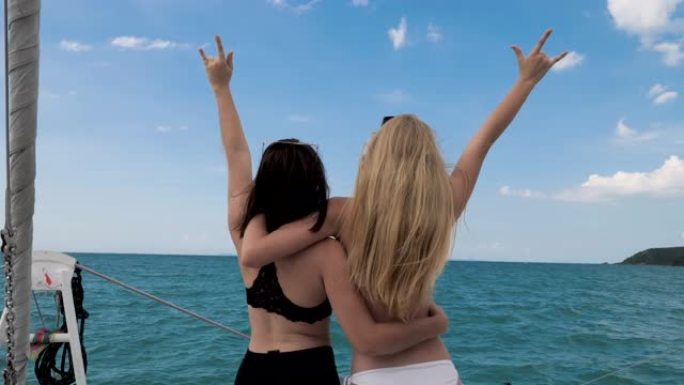 两个美丽的女孩在海上的游艇上跳舞