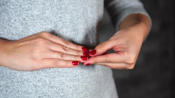 紧张的女人挑她的红色指甲。女人的手靠近她的指甲。女性用手指从指甲上剥下红色指甲油