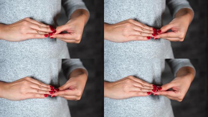紧张的女人挑她的红色指甲。女人的手靠近她的指甲。女性用手指从指甲上剥下红色指甲油