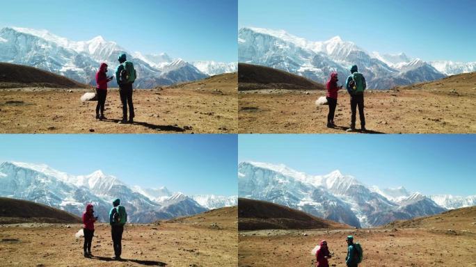 一对夫妇从尼泊尔喜马拉雅山安纳普尔纳巡回赛的一部分冰湖欣赏风景。安纳普尔纳链在后面，被雪覆盖。晴朗的