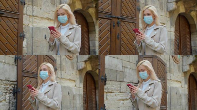 在老城的街道上使用智能手机戴着防护面具的年轻女子。忧心忡忡的女孩正在寻找关于新型冠状病毒肺炎的新闻。
