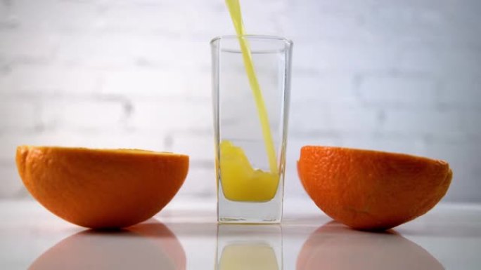 鲜榨的橙汁倒入桌子上的玻璃杯中，旁边有橙片。白色背景上有水果的清爽黄色饮料