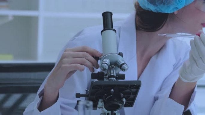 女科学家正在实验室使用显微镜进行研究。