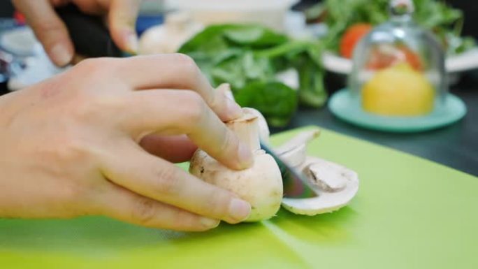 厨师在厨房切蘑菇，特写。女性的手将蘑菇切成薄片。女人切蔬菜。披萨配料。烹饪过程。