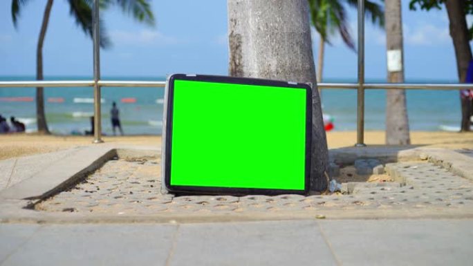 电视站在海滩上。绿屏电视。您可以用所需的素材或图片替换绿色屏幕。