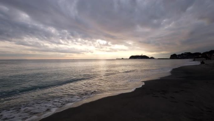 日本神奈川江之岛的日落。海浪对着海滩。