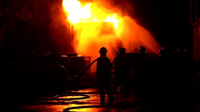 消防员训练喷水水幕，一群消防员帮助灭火。工业工厂发生火灾。救援、教育、应急和团队合作理念。