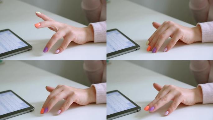 用平板电脑拍拍漂亮修指甲的女性手的特写镜头，在办公室的室内等待桌子上轻拍