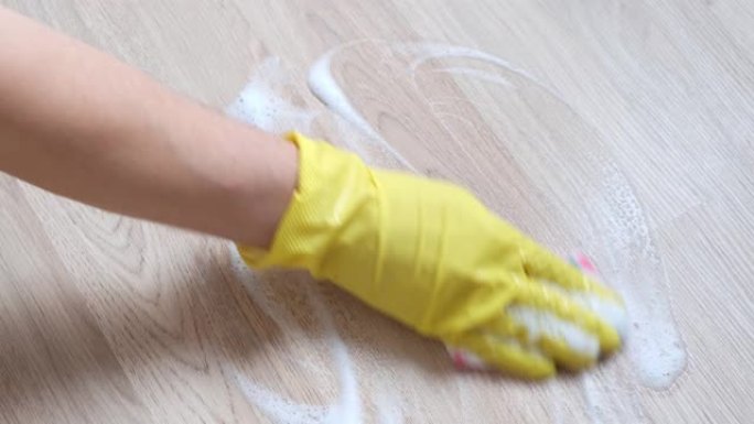 女性双手戴着黄色橡胶手套清洁公寓。