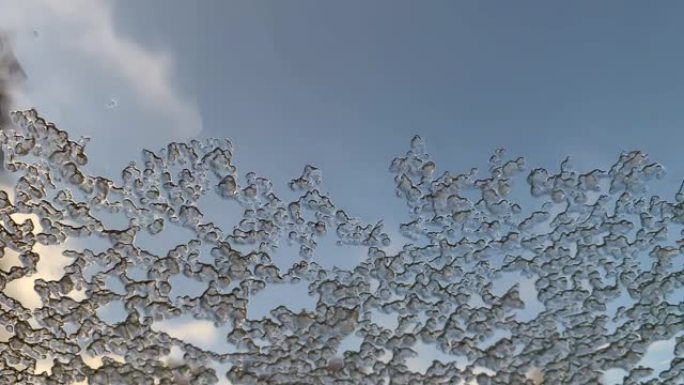 湿冰落在汽车的湿玻璃上，水和雪花流下来