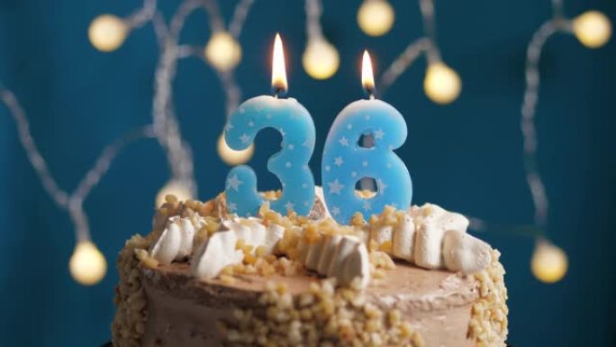 蓝色背景上有36号蜡烛的生日蛋糕。蜡烛吹灭了。慢动作和特写视图