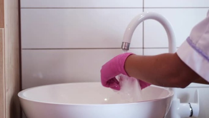 沙龙中手套洗涤工具中女性手的裁剪视图