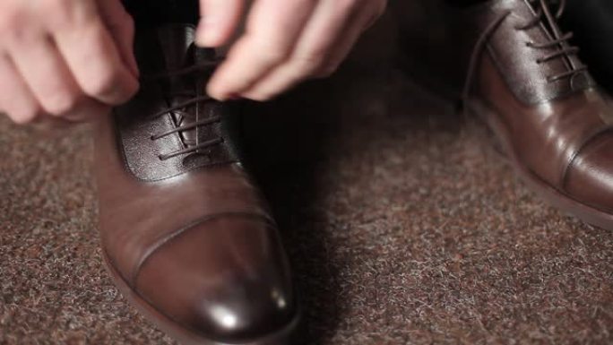 商人男子在房间里把鞋带绑在棕色靴子上。一个男人穿鞋。