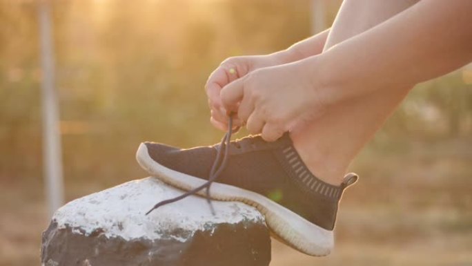 亚洲女人系鞋准备在早晨的阳光下在旅途中锻炼。健身与健康生活方式，开始锻炼理念