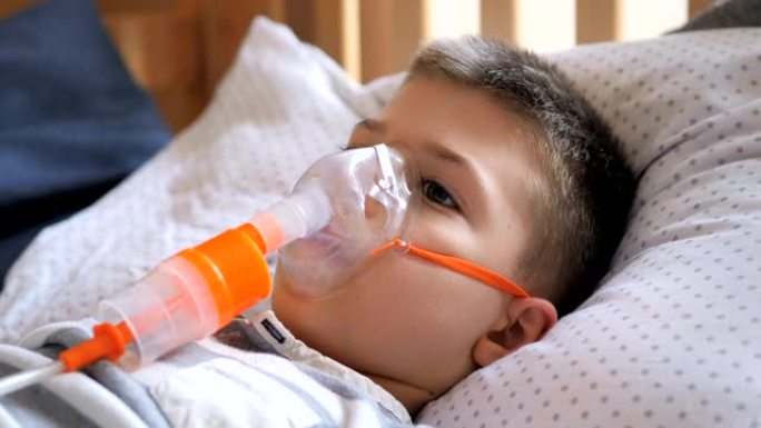 小男孩接受喷雾器治疗，咳嗽。小男孩使用雾化器进行治疗性吸入