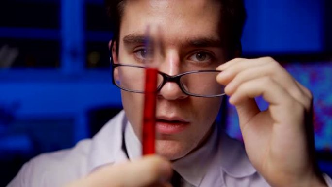 放大年轻化学科学家的特写镜头，检查试管中的红色液体并脱下眼镜以探索令人惊讶的实验结果，在实验室中看起