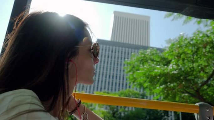 在夏天阳光明媚的日子里，年轻美丽的女人在乘坐旅游巴士环游城市时看着马德里的风景。西班牙。4K