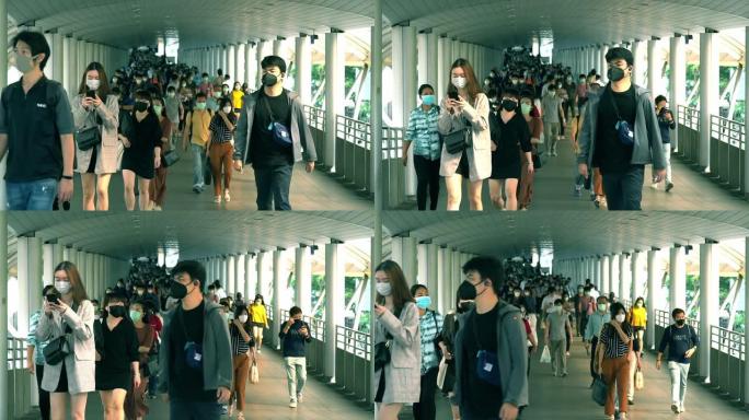 在泰国曼谷Chong-nonsi BTS站的公共交通系统工作人员之后，许多人戴着口罩的慢动作在桥梁高