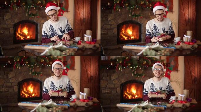 大胡子的男人坐在壁炉附近的礼物上系弓。戴着圣诞帽的家伙用纸包装盒子，用冷杉树枝，圆锥体，甘蔗糖果装饰