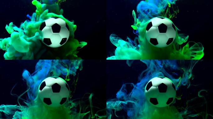 足球背景惊人。黑色背景上的水中绿色和蓝色墨水