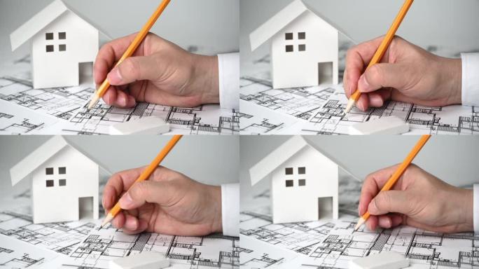 一个手里拿着铅笔画建筑图纸的人。
