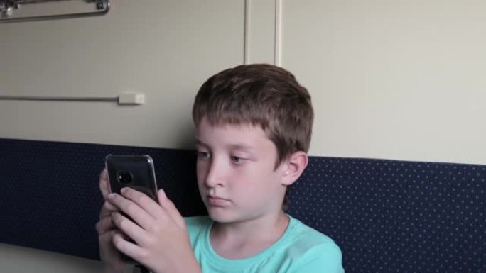 一个青春期男孩在坐火车，旅行和旅行时在智能手机上玩游戏