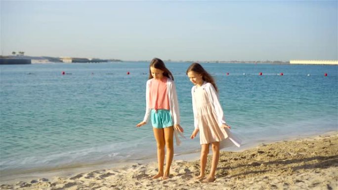 小快乐有趣的女孩在热带海滩一起玩有很多乐趣。