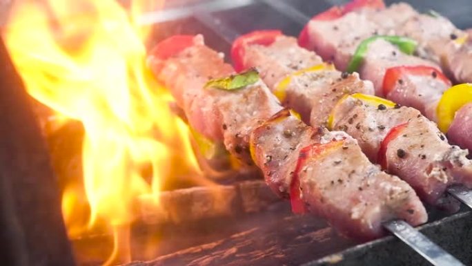 肉串上多汁，嫩的烤肉串。将肉和胡椒刺穿并在煤上油炸。肉上撒上胡椒和香料。在明火上烹饪。慢动作特写。