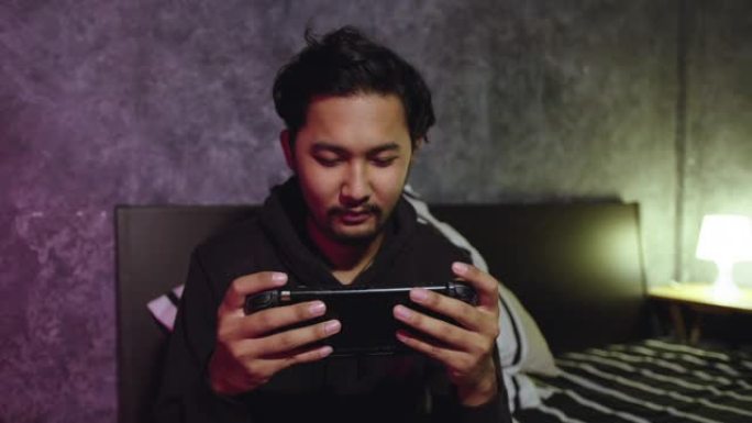 年轻的亚洲男子在家玩电子游戏