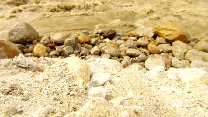 沙子在泥泞的山河的岩石岸上破碎
