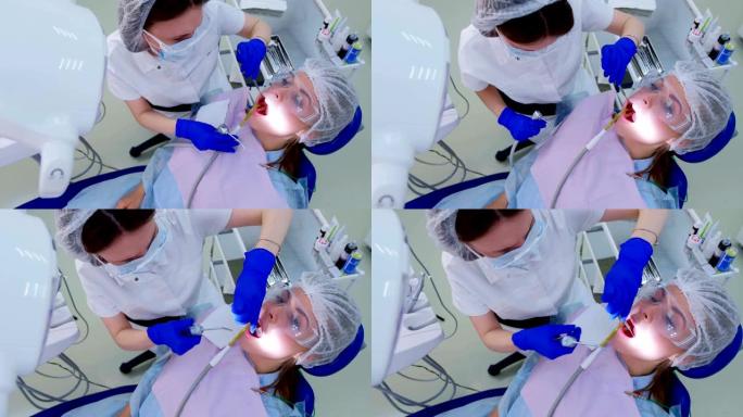 牙医在超声波清洁期间使用唾液喷射器将水倒在女性牙齿上。