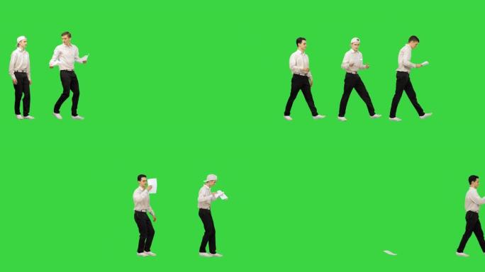 在创意办公办公室中，工作人员走路，看着绿色屏幕上跳舞的报纸，色度键