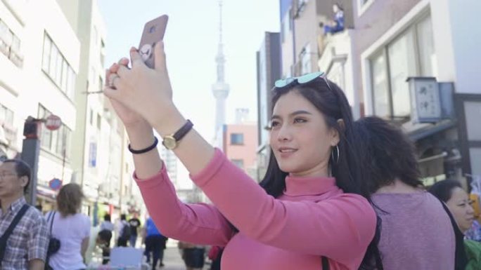年轻的女性游客在日本的步行街上拍照