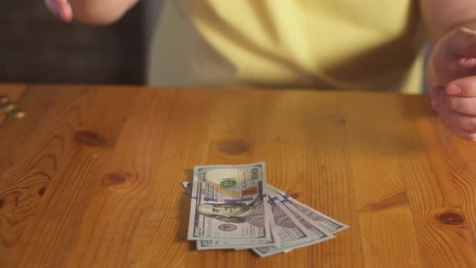 男人把现金100美元钞票扔在桌子上。商人手里拿着美元货币现金钞票。货币利润计算。国内经济金融。个人预